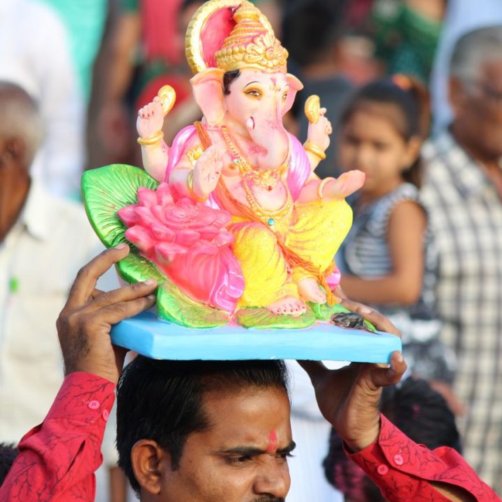 man holding figure of ganesha on head