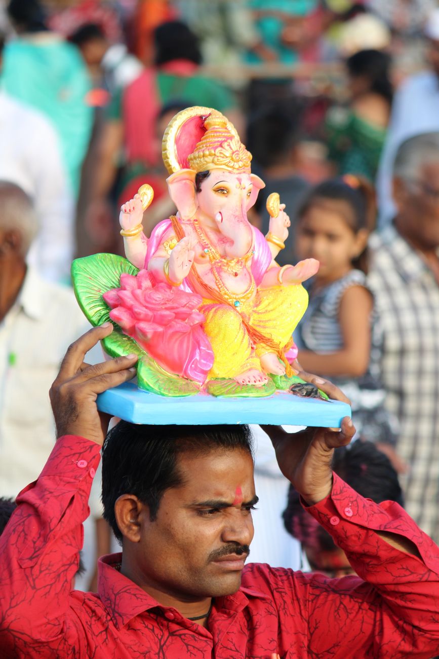 man holding figure of ganesha on head