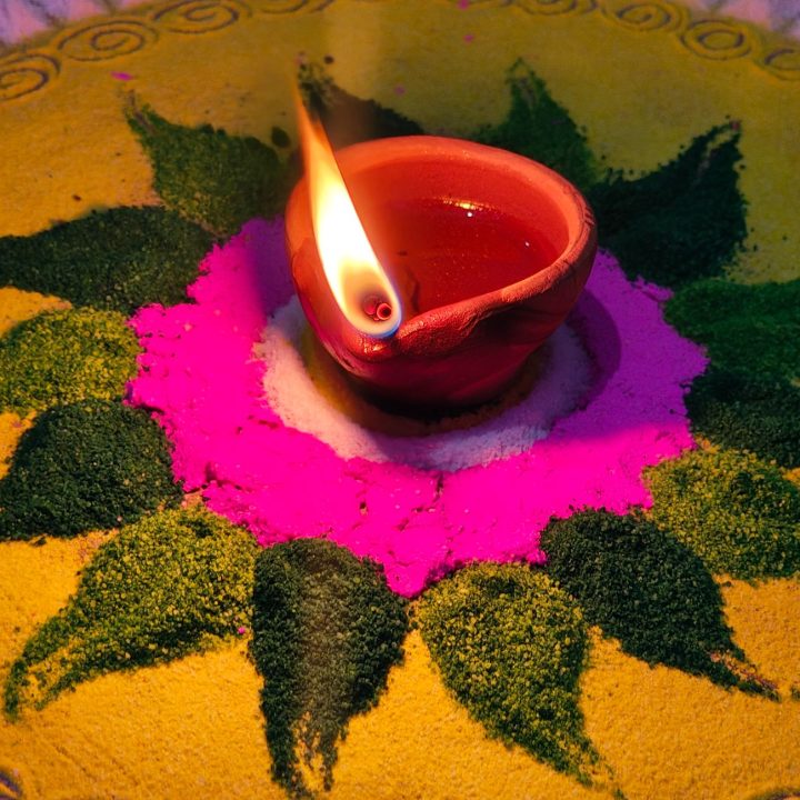 vibrant diwali rangoli with lit clay lamp