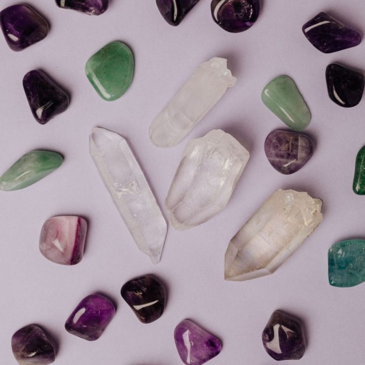 assorted various crystals and polished semiprecious stones against gray background