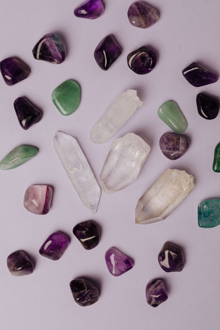 assorted various crystals and polished semiprecious stones against gray background